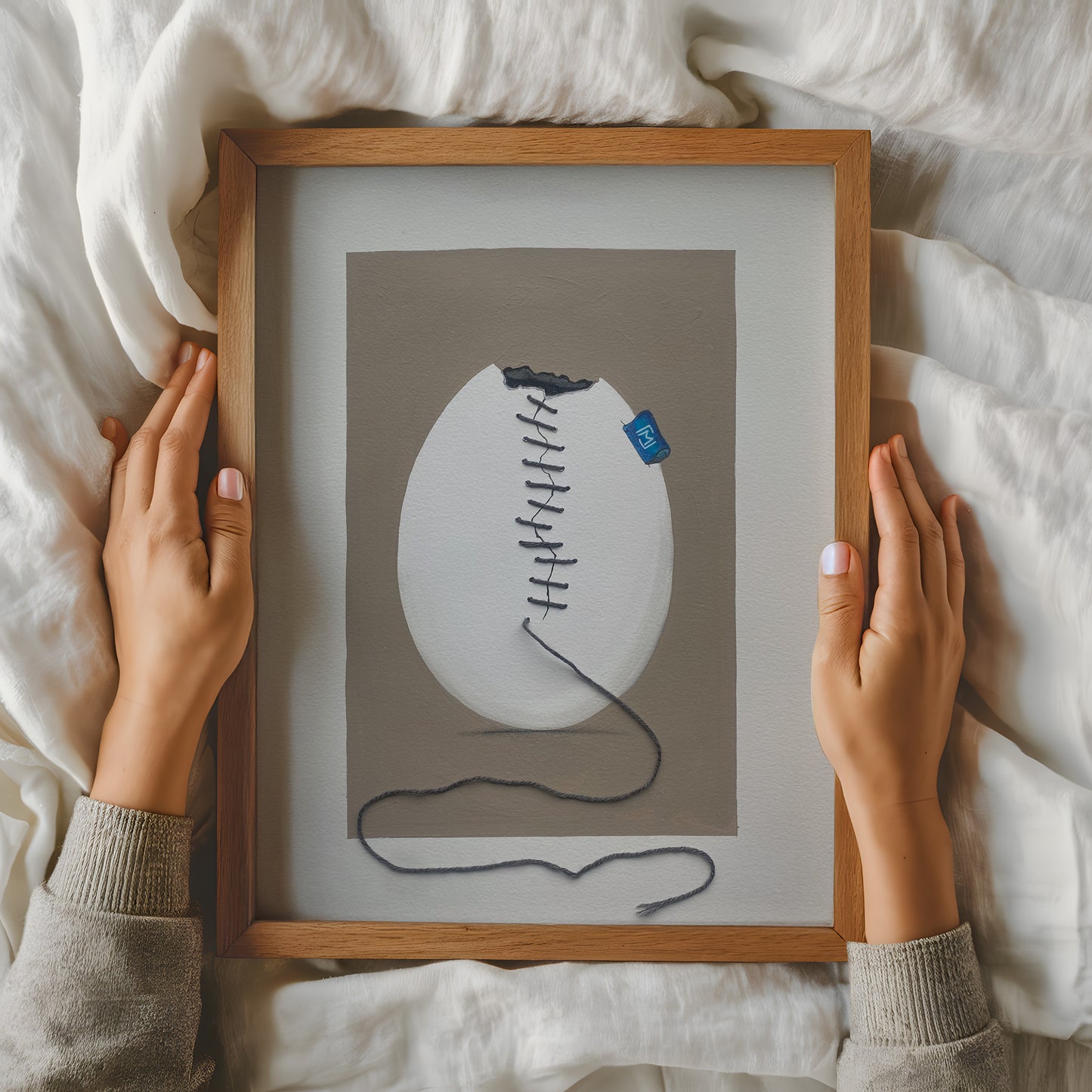 Originalt kunstværk med et revnet strudseæg syet sammen med fin bambustråd. Ægget er malet med akryl og blyant på kraftigt kunstpapir og har et roligt, humoristisk udtryk. Ægte tråd skaber synlig tekstur og dybde i værket, som passer ind i moderne nordisk indretning.