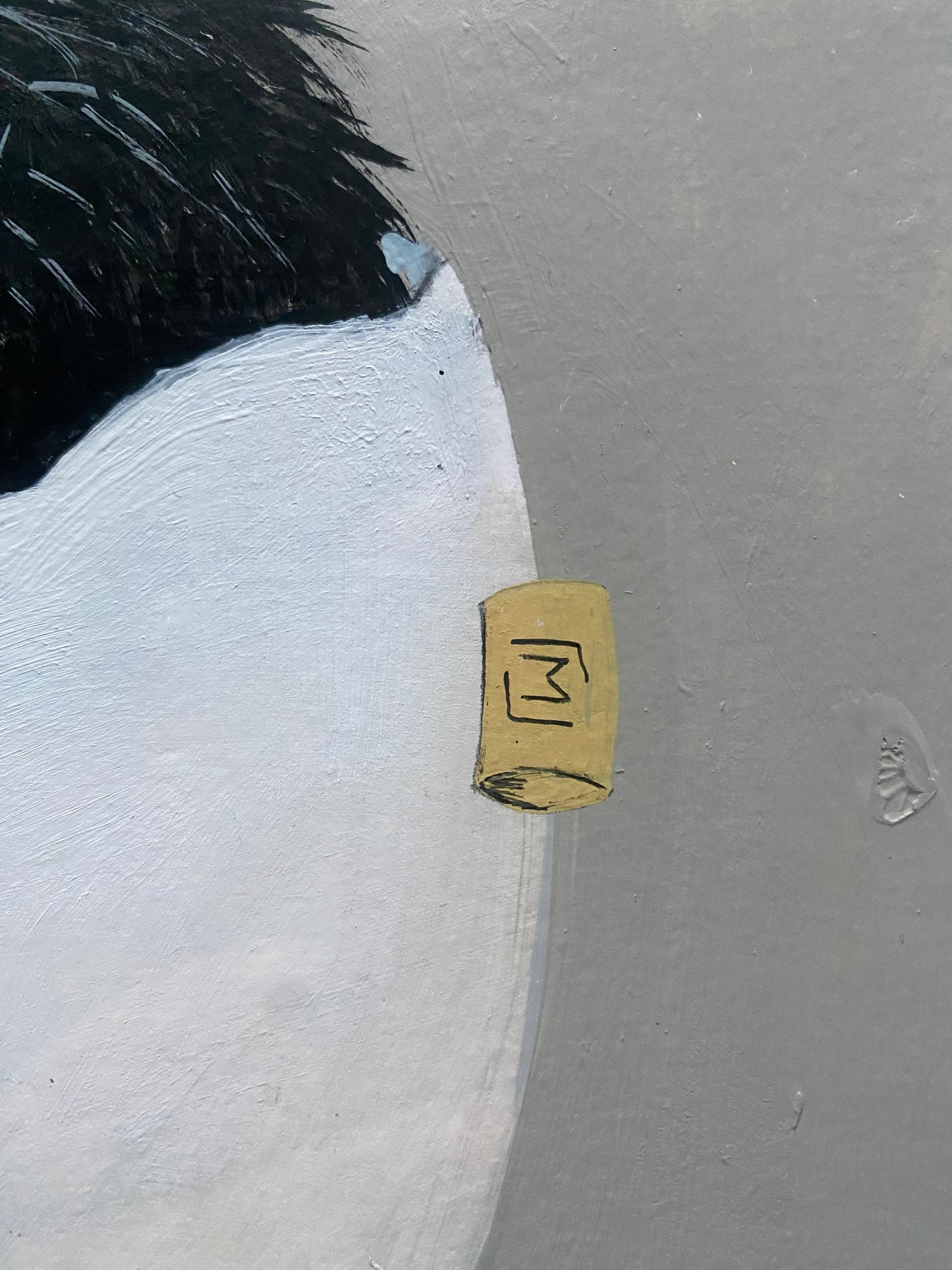 Indrammet kunstværk med et hvidt, revnet æg, der står på gule fødder. Ægget er syet sammen med mørk tråd, og en løs tråd fortsætter ned foran billedet. Øverst ses mørkt, børsteagtigt fyld. Baggrunden er afdæmpet grå.