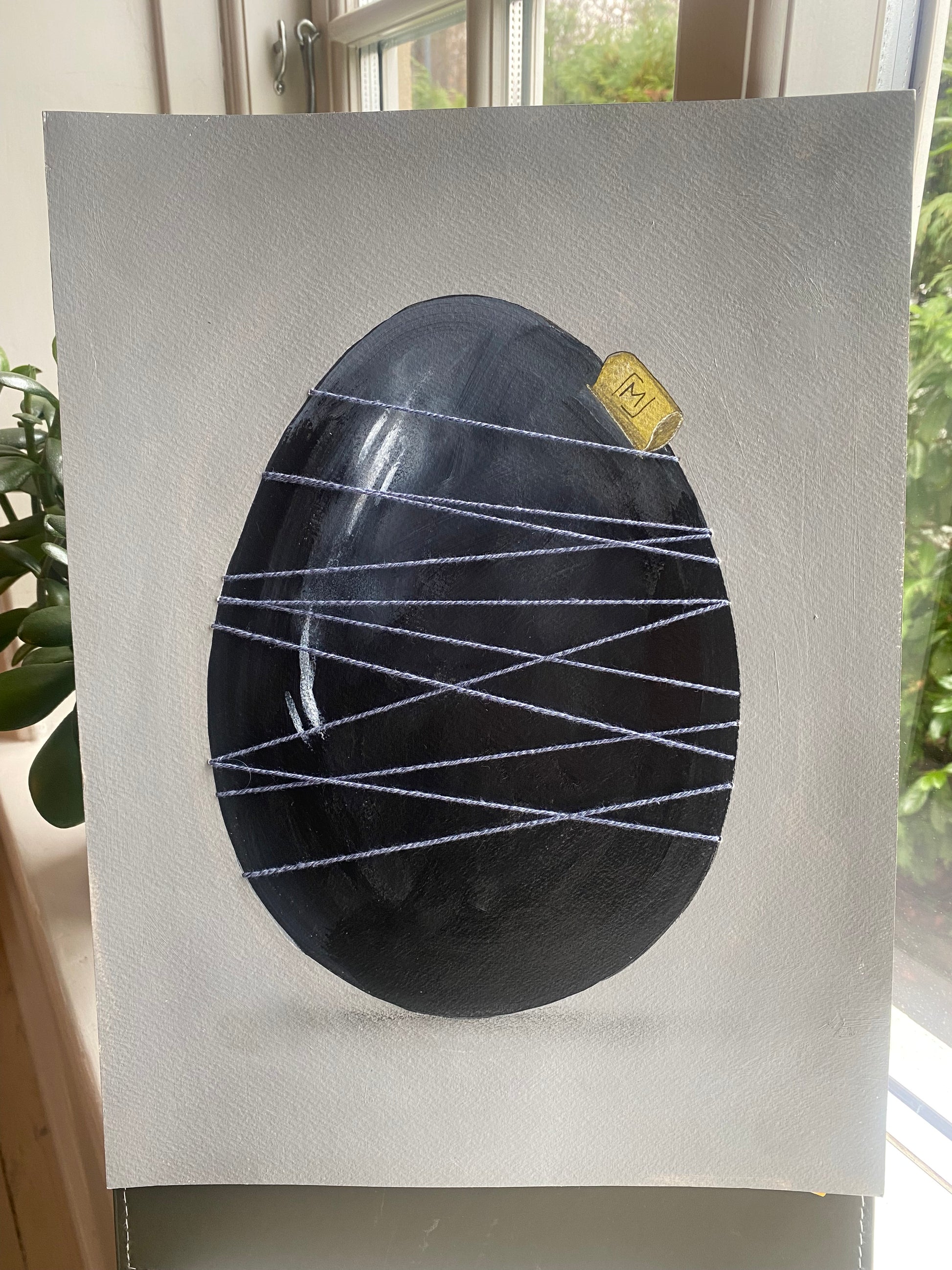 Mørkt håndmalet æg holdt sammen af lys tråd. Original kunst med roligt udtryk, synlige lag og fokus på materialitet og balance.