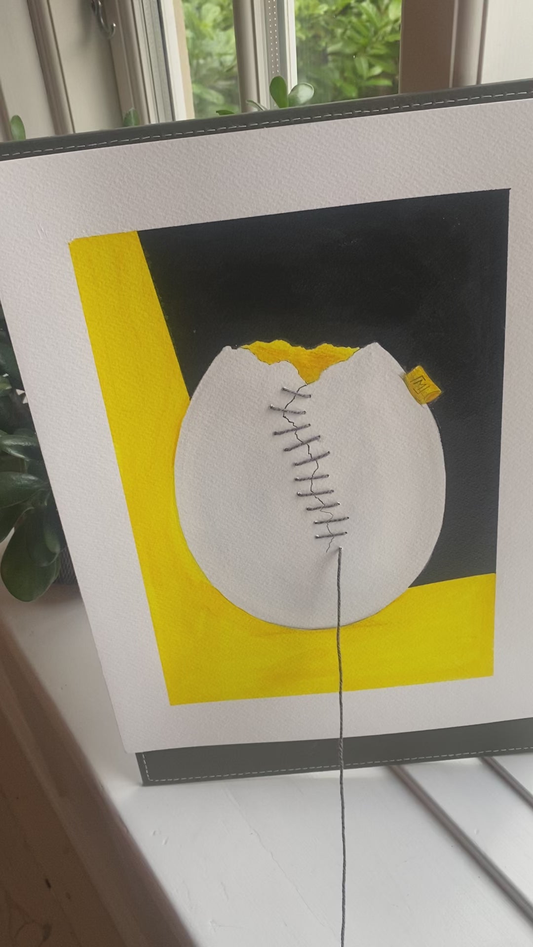 Abstrakt kunstværk med et hvidt æg på gul og mørk baggrund. Ægget er revnet og samlet med synlig grå tråd, der løber hen over overfladen. Gule felter skaber varme og kontrast i et enkelt, håndlavet udtryk.
