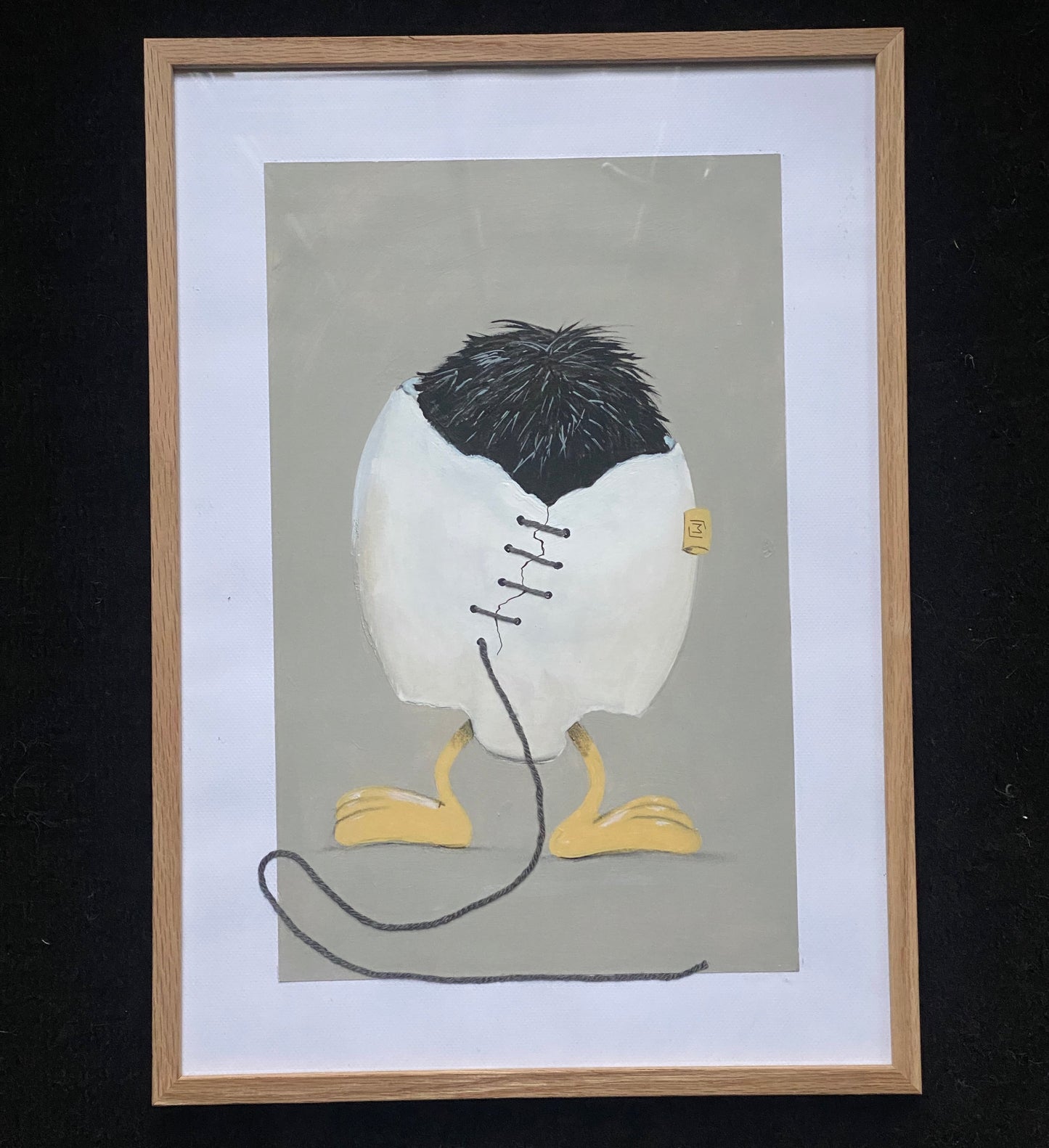 Indrammet kunstværk med et hvidt, revnet æg, der står på gule fødder. Ægget er syet sammen med mørk tråd, og en løs tråd fortsætter ned foran billedet. Øverst ses mørkt, børsteagtigt fyld. Baggrunden er afdæmpet grå.