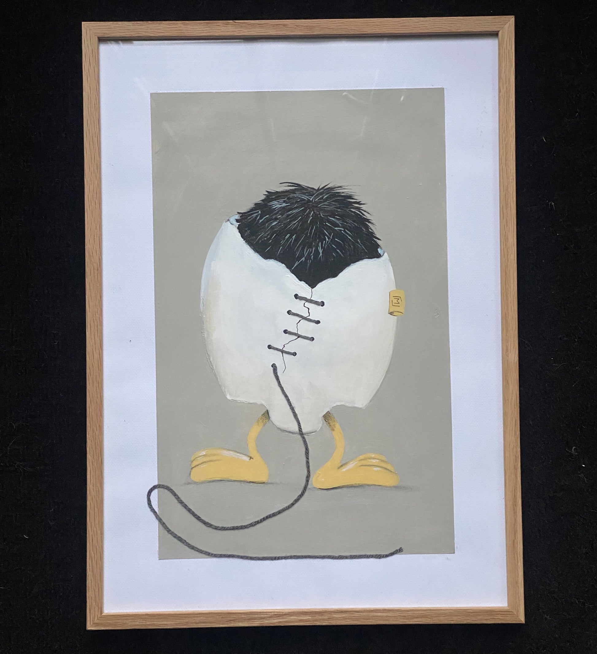 Indrammet kunstværk med et hvidt, revnet æg, der står på gule fødder. Ægget er syet sammen med mørk tråd, og en løs tråd fortsætter ned foran billedet. Øverst ses mørkt, børsteagtigt fyld. Baggrunden er afdæmpet grå.